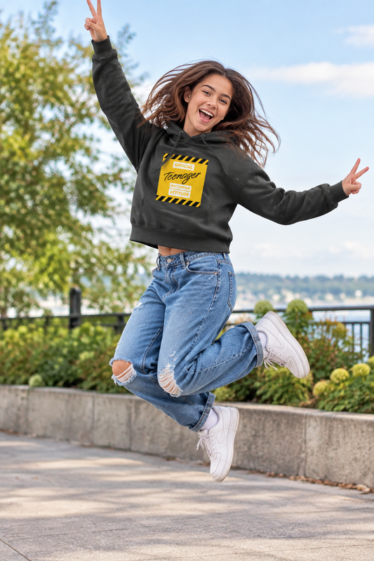 Black cropped hoodie with a yellow warning label on a white background